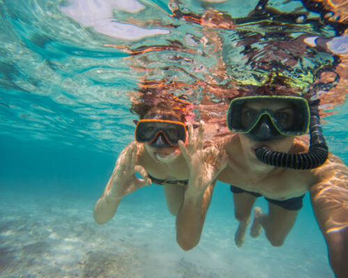 boy and girl in love with mask and flippers swim in clear blue water and taking a self portrait picture
