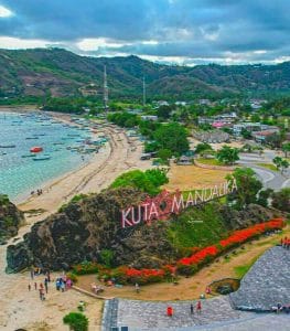 Scenic view of Kuta Mandalika beach with boats and lush hills.