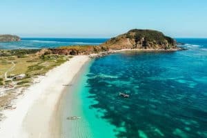 Scenic view of Kuta Beach with turquoise waters and surrounding hills.